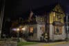 At night, a two-story building designed in the Germanic style. On a fence jutting out from the first floor is a sign that reads "Biergarten."