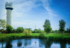 A panoramic view of a field of green grass with the Franklin, Wisconsin, water tower on the left side in the background.