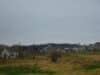 In the foreground is an empty field with rows of houses in the background in Fitchburg, Wisconsin.