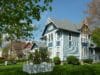 In the foreground stands a three-story house with another house in the background and trees in Stoughton, Wisconsin.