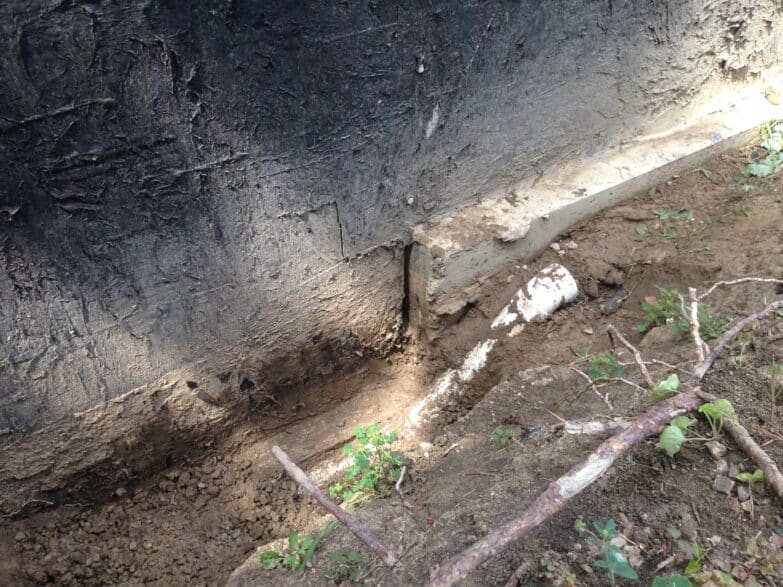 A close up photo of a vertical crack in a wall where the wall meets the ground.