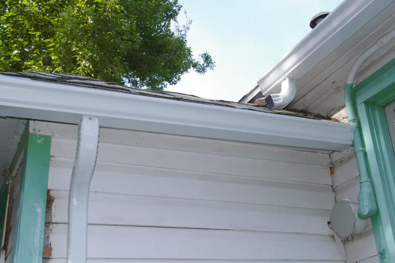 A close up photo of a gutter on the edge of a roof on a house.