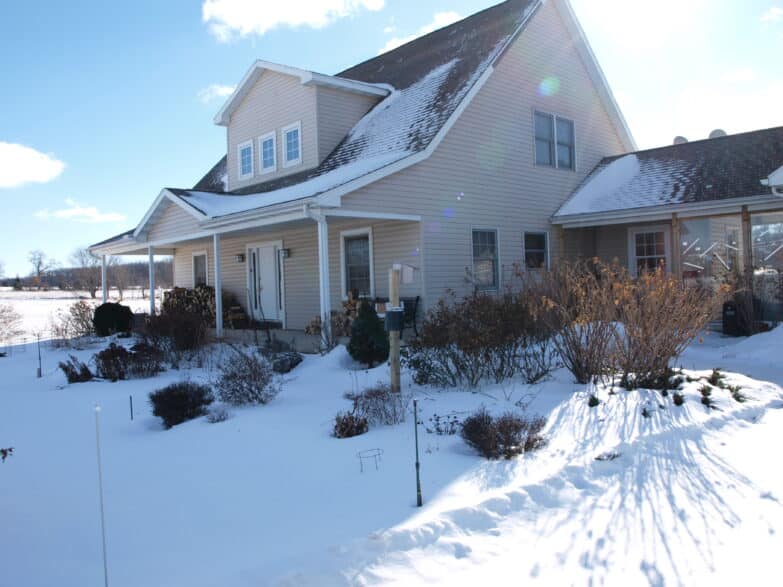 A two-story house in winter with a snow-filled lawn.