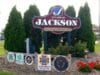 The official sign at the entrance of the Village of Jackson, Wisconsin, which reads, “Village of Jackson: Taking the lead in Washington County.” Trees surround the sign