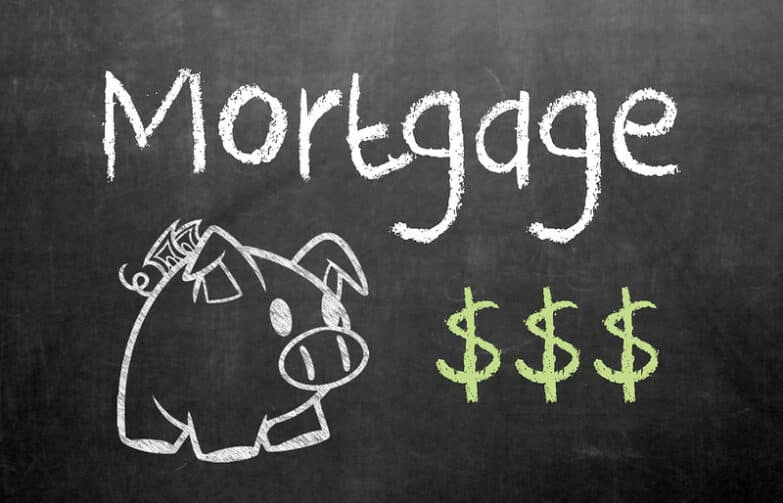 A blackboard with the word "Mortgage" written in white chalk. Below that is white-chalk drawing of a pig next to dollar signs in green chalk.