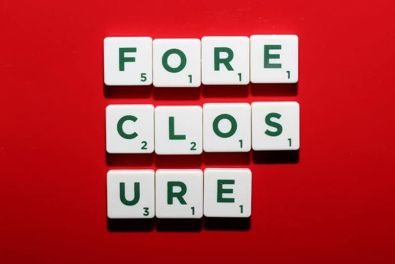 A red background with Scrabble letter pieces on it spelling "FORECLOSURE" broken into three lines.