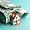 An AI-generated image of a large wad of money and a toy house in front of it.