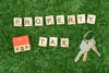 The words "property tax" written in letter tiles. A key and a small wooden house nearby, associated to selling property with delinquent taxes.