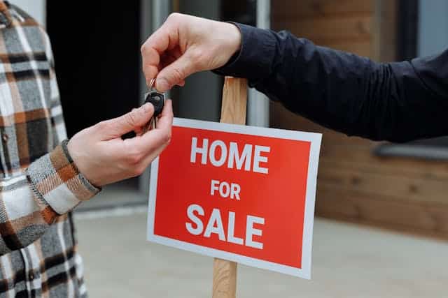 Hands holding house keys in front of for sale sign, symbolizing Sell Your House Fast process
